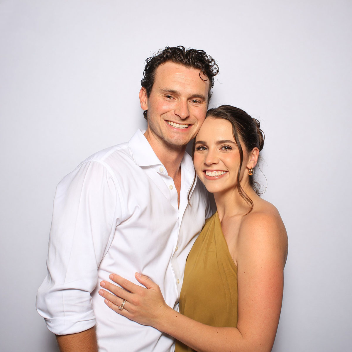 Couple photographed in the booth against a white backdrop
